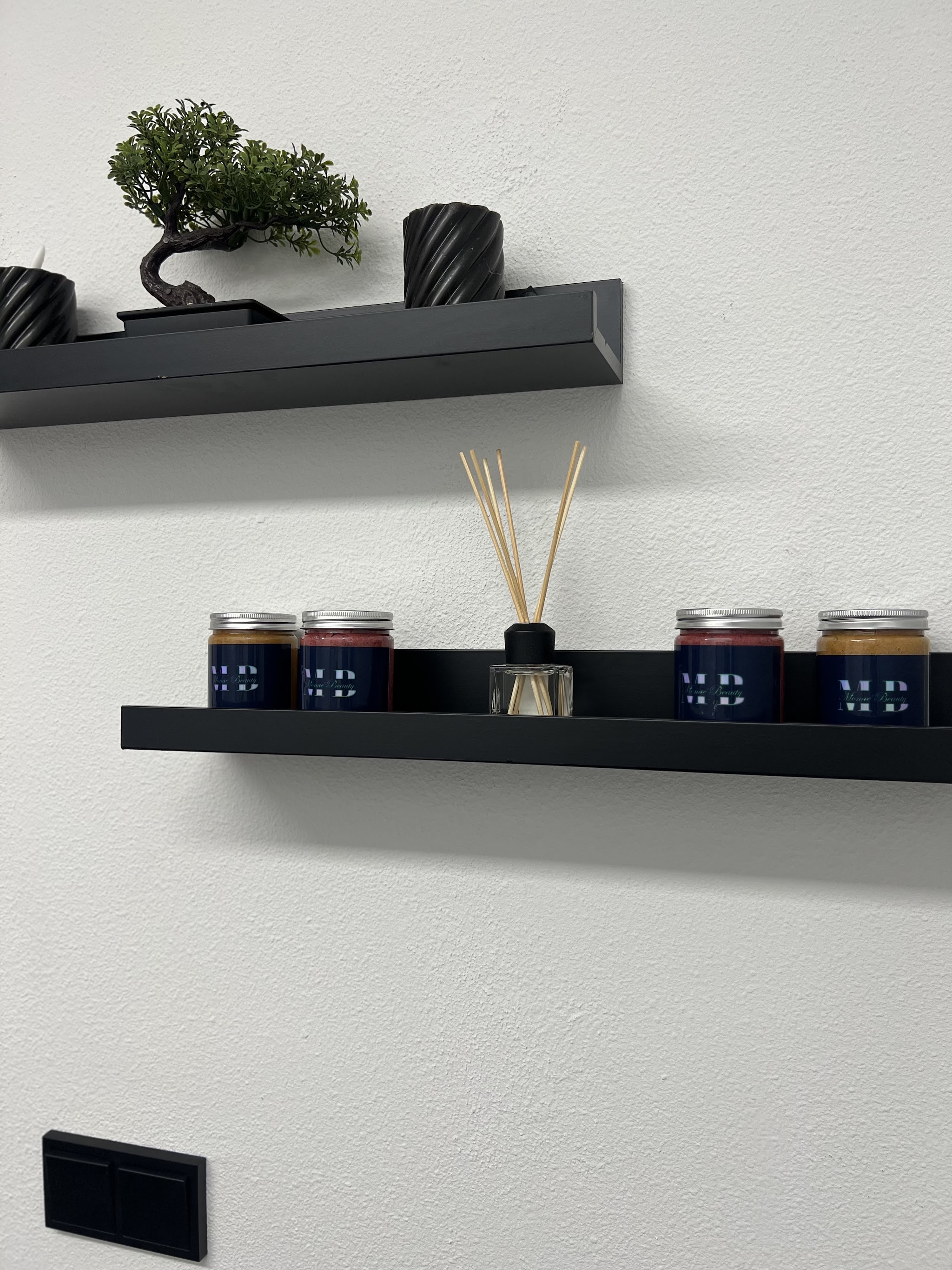 Zwarte wandplanken in de salon met potten wax, een bonsai en een geurstokjesflesje