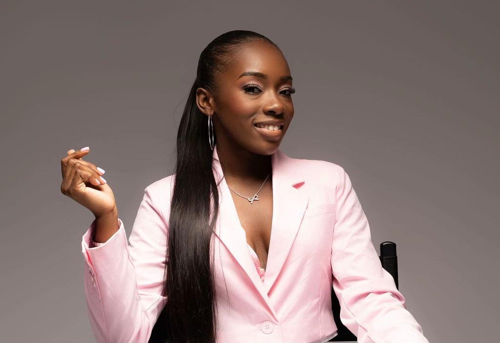 Desha van Monaé Beauty in een roze blazer, lachend in een regisseursstoel